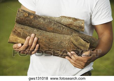 Mid section view of a young man holding firewood View Large Photo Image Stock Photo - Mid section view of a young man holding firewood. Fotosearch