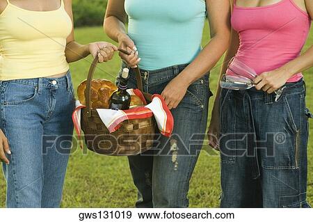 Mid section view of three women standing together holding a picnic basket View Large Photo Image Stock Photo - Mid section view of three women standing together holding a picnic basket. Fotosearch