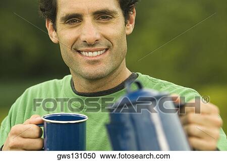 Portrait of a mid adult man holding a coffee cup and a kettle View Large Photo Image Stock Image - Portrait of a mid adult man holding a coffee cup and a kettle. Fotosearch