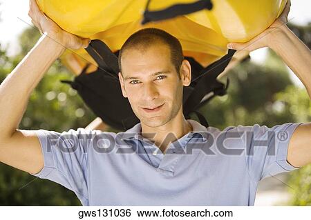 Portrait of a young man carrying a kayak on his head View Large Photo Image Stock Photograph - Portrait of a young man carrying a kayak on his head. Fotosearch