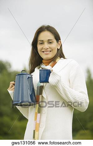 Portrait of a young woman holding a cup and a kettle View Large Photo Image Stock Photograph - Portrait of a young woman holding a cup and a kettle. Fotosearch