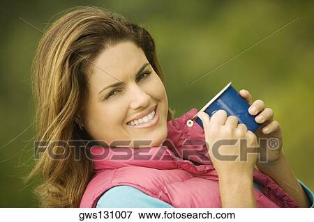 Portrait of a young woman holding a mug View Large Photo Image Stock Photo - Portrait of a young woman holding a mug. Fotosearch
