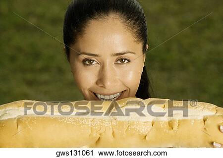 Portrait of a young woman holding a loaf of bread View Large Photo Image Stock Image - Portrait of a young woman holding a loaf of bread. Fotosearch