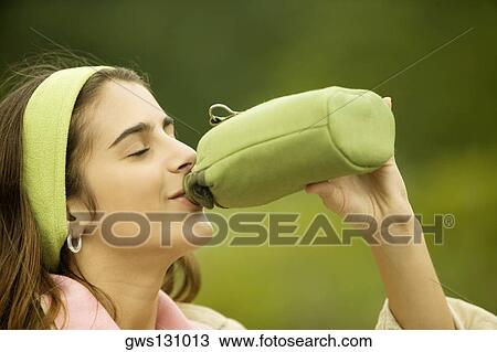 Side profile of a girl drinking water from a bottle View Large Photo Image Stock Image - Side profile of a girl drinking water from a bottle. Fotosearch