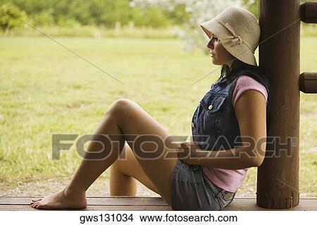 Side profile of a young woman sitting on a porch View Large Photo Image Picture - Side profile of a young woman sitting on a porch. Fotosearch