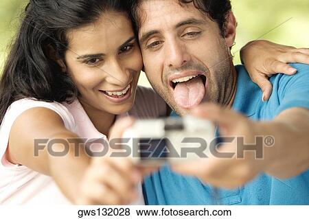 Close-up of a mid adult man and a young woman taking a photograph of themselves View Large Photo Image Stock Photo - Close-up of a mid adult man and a young woman taking a photograph of themselves. Fotosearch