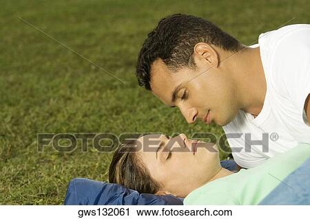 Close-up of a young man leaning over a young woman on the lawn View Large Photo Image Stock Image - Close-up of a young man leaning over a young woman on the lawn. Fotosearch