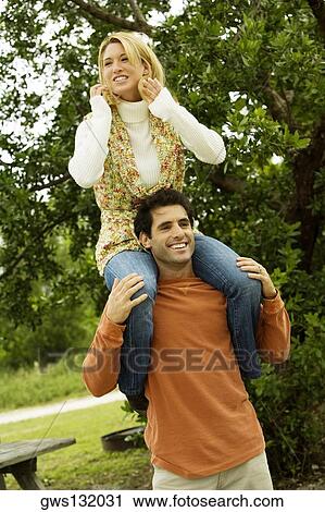 Mid adult man carrying a young woman on his shoulders View Large Photo Image Stock Image - Mid adult man carrying a young woman on his shoulders. Fotosearch