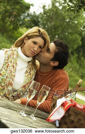Mid adult man kissing a young woman View Large Photo Image Stock Photograph - Mid adult man kissing a young woman. Fotosearch