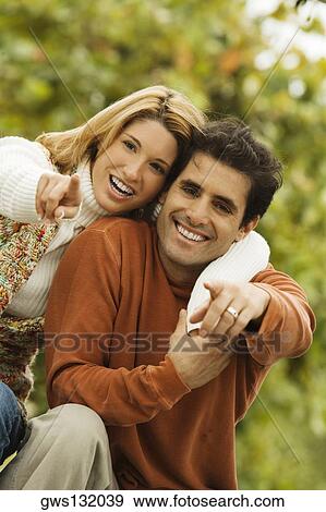 Portrait of a young woman with her arm around a mid adult man pointing forward View Large Photo Image Stock Photo - Portrait of a young woman with her arm around a mid adult man pointing forward. Fotosearch