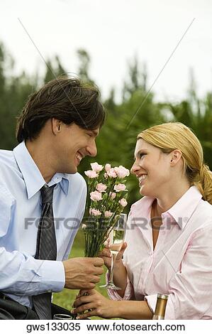Stock Photography - Businessman and a businesswoman holding a bunch of flowers looking at each other. Fotosearch
