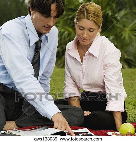 Businessman and a businesswoman reading a magazine in the park View Large Photo Image Stock Photo - Businessman and a businesswoman reading a magazine in the park. Fotosearch