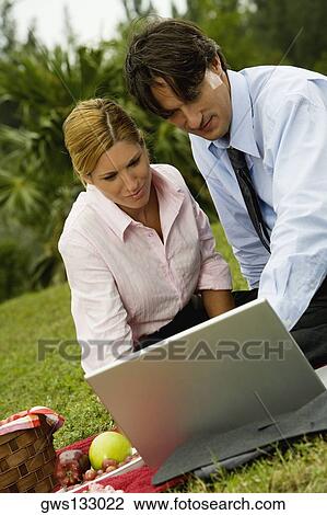 Close-up of a businessman and a businesswoman working on a laptop in the park View Large Photo Image Stock Image - Close-up of a businessman and a businesswoman working on a laptop in the park. Fotosearch