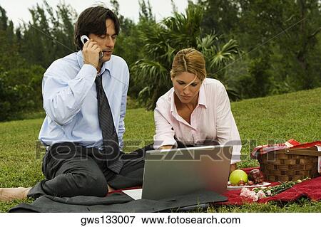 Close-up of a businessman and a businesswoman working on a laptop in the park View Large Photo Image Stock Photo - Close-up of a businessman and a businesswoman working on a laptop in the park. Fotosearch