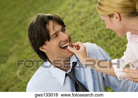 Stock Photograph - Close-up of a businesswoman feeding a cherry to a businessman. Fotosearch