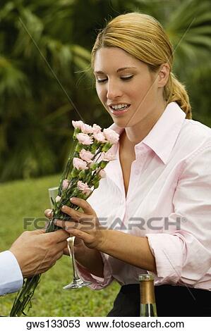 Stock Image - Close-up of a man giving a bunch of flowers to a businesswoman. Fotosearch