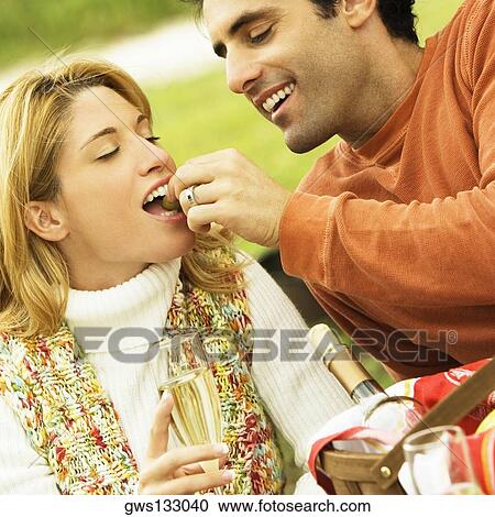 Close-up of a mid adult man feeding a young woman View Large Photo Image Stock Image - Close-up of a mid adult man feeding a young woman. Fotosearch