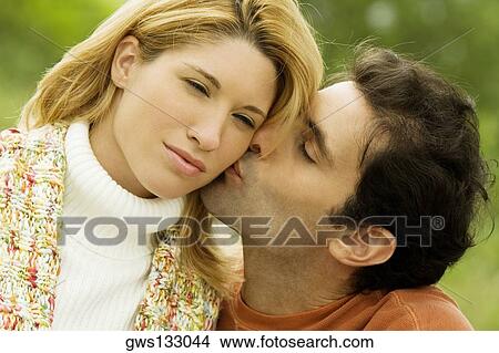 Close-up of a mid adult man kissing a young woman View Large Photo Image Picture - Close-up of a mid adult man kissing a young woman. Fotosearch