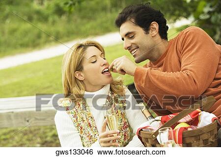Mid adult man feeding a young woman View Large Photo Image Stock Photograph - Mid adult man feeding a young woman. Fotosearch