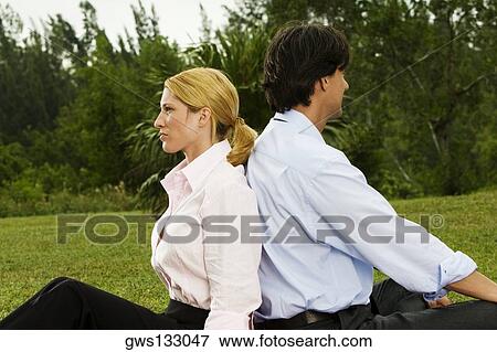 Side profile of a businessman and a businesswoman sitting back to back in the park View Large Photo Image Stock Photo - Side profile of a businessman and a businesswoman sitting back to back in the park. Fotosearch