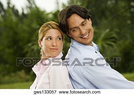Side profile of a businessman and a businesswoman sitting back to back in the park View Large Photo Image Stock Photo - Side profile of a businessman and a businesswoman sitting back to back in the park. Fotosearch
