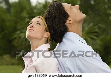 Side profile of a businessman and a businesswoman sitting back to back in the park View Large Photo Image Stock Photo - Side profile of a businessman and a businesswoman sitting back to back in the park. Fotosearch