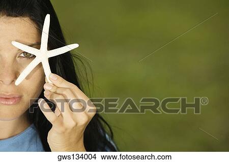 Portrait of a young woman covering her eye with a starfish View Large Photo Image Picture - Portrait of a young woman covering her eye with a starfish. Fotosearch