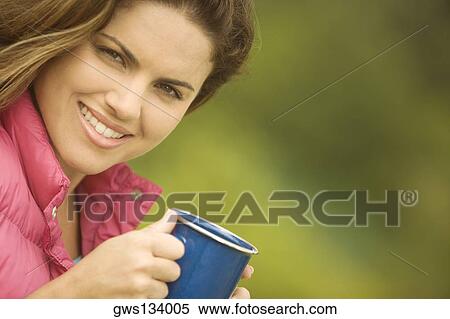 Portrait of a young woman holding a mug View Large Photo Image Stock Photography - Portrait of a young woman holding a mug. Fotosearch