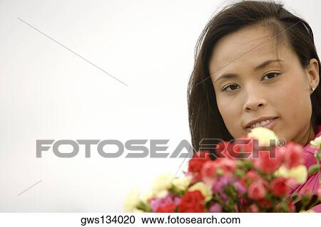 Portrait of a young woman holding a bunch of flowers View Large Photo Image Stock Image - Portrait of a young woman holding a bunch of flowers. Fotosearch