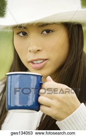 Stock Image - Portrait of a young woman holding a coffee cup. Fotosearch