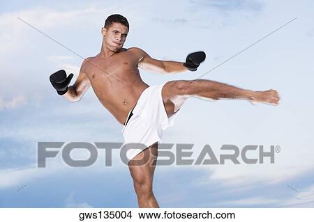 Low angle view of a young man kicking View Large Photo Image Picture - Low angle view of a young man kicking. Fotosearch