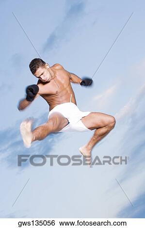 Low angle view of a young man kicking in mid-air View Large Photo Image Stock Photograph - Low angle view of a young man kicking in mid-air. Fotosearch