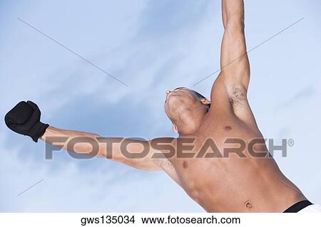 Low angle view of a young man with his arms raised View Large Photo Image Picture - Low angle view of a young man with his arms raised. Fotosearch