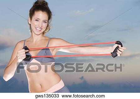 Portrait of a young woman exercising with a resistance band View Large Photo Image Stock Image - Portrait of a young woman exercising with a resistance band. Fotosearch
