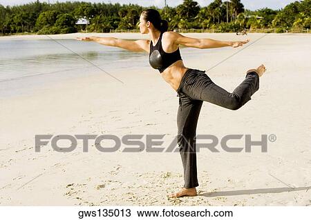 Stock Image - Young woman practicing martial arts on the beach. Fotosearch