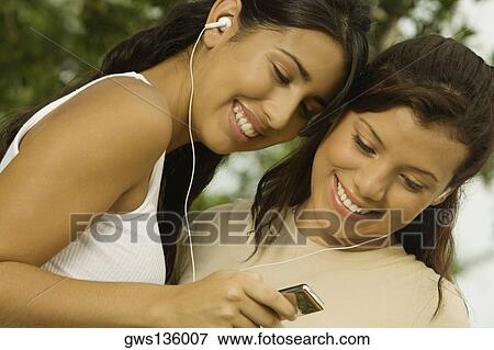 Close-up of two teenage girls holding an MP3 player listening to music View Large Photo Image Stock Photo - Close-up of two teenage girls holding an MP3 player listening to music. Fotosearch