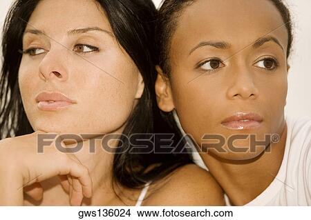 Picture - Close-up of two young women looking away. Fotosearch