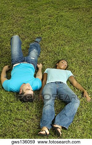 High angle view of a young couple lying on the grass View Large Photo Image Stock Photo - High angle view of a young couple lying on the grass. Fotosearch