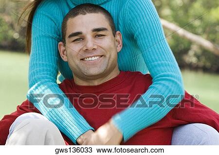 Stock Image - Mid section view of a young woman embracing a young man. Fotosearch
