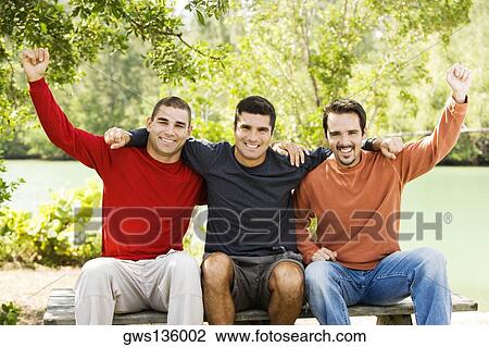 Portrait of a mid adult man and two young men sitting on a bench View Large Photo Image Stock Image - Portrait of a mid adult man and two young men sitting on a bench. Fotosearch