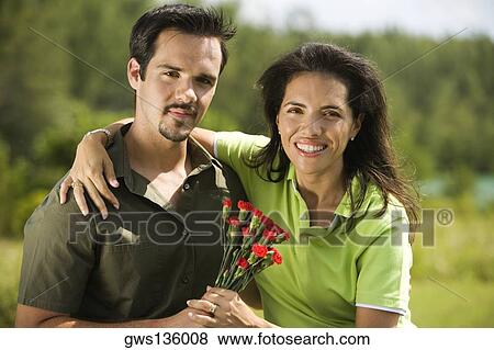 Stock Photo - Portrait of a young couple holding a bunch of roses. Fotosearch