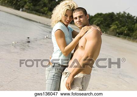 Portrait of a young couple standing on the beach View Large Photo Image Stock Photo - Portrait of a young couple standing on the beach. Fotosearch