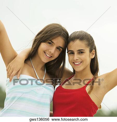 Portrait of two girls smiling with their hands raised View Large Photo Image Stock Photograph - Portrait of two girls smiling with their hands raised. Fotosearch