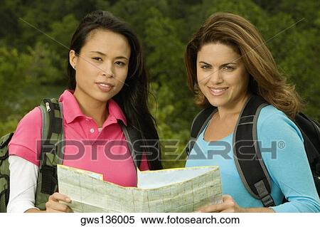 Portrait of two young women holding a map smiling View Large Photo Image Stock Photography - Portrait of two young women holding a map smiling. Fotosearch