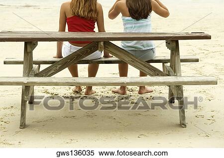 Rear view of two teenage girls sitting on a wooden bench View Large Photo Image Stock Photography - Rear view of two teenage girls sitting on a wooden bench. Fotosearch