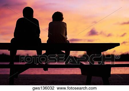 Stock Image - Silhouette of two boys sitting on a picnic table. Fotosearch