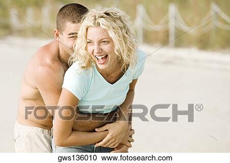 Young man embracing a young woman from behind View Large Photo Image Stock Image - Young man embracing a young woman from behind. Fotosearch