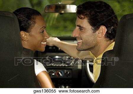 Stock Photography - Young woman and a mid adult man sitting in a car looking at each other. Fotosearch