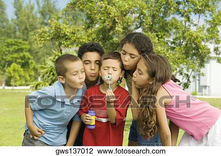 Stock Image - Boys and girls blowing bubble wands. Fotosearch