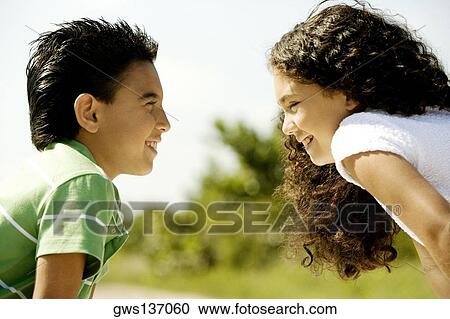 Close-up of a boy and a girl looking at each other smiling View Large Photo Image Stock Image - Close-up of a boy and a girl looking at each other smiling. Fotosearch